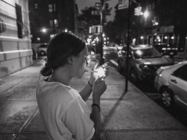 black and white smoking woman on the street