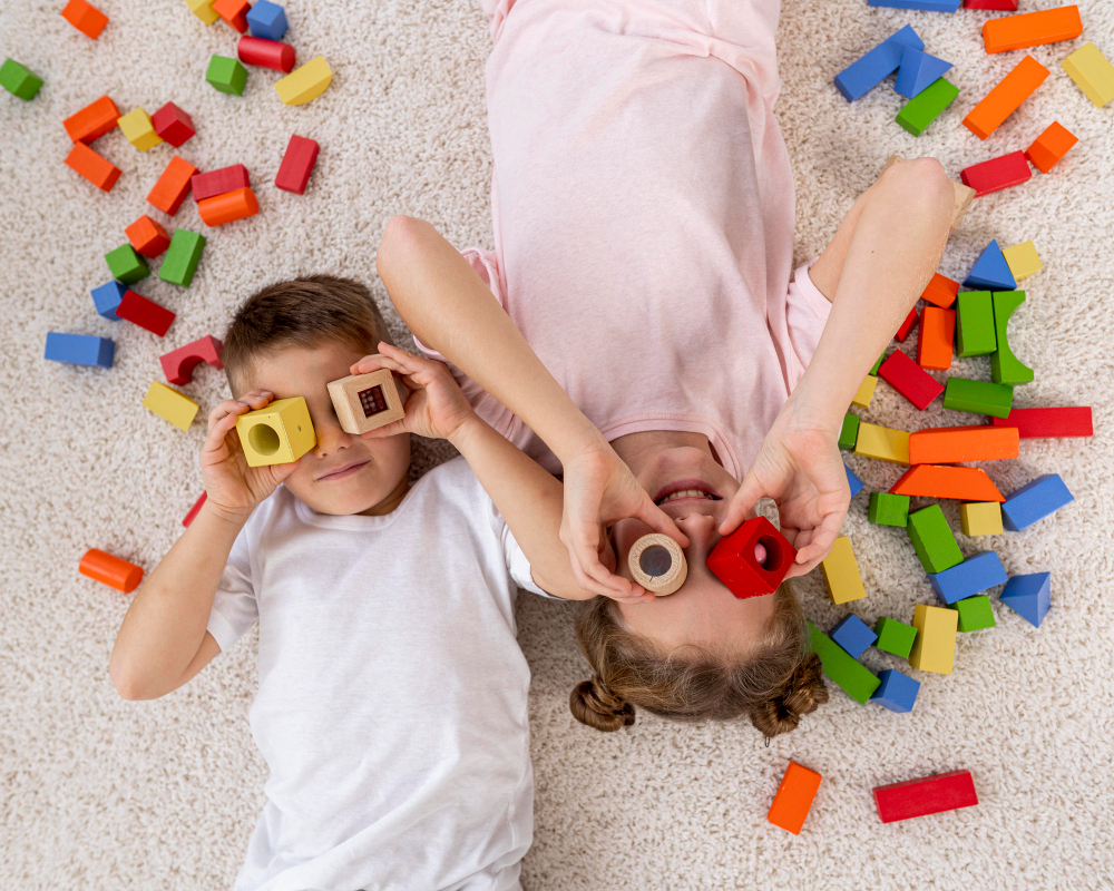 two kids on the carpet playing with colourful blocks